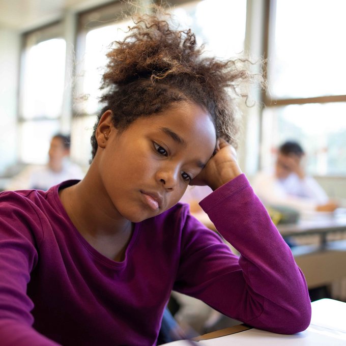 Trauriges Schulmädchen in einer Klasse 