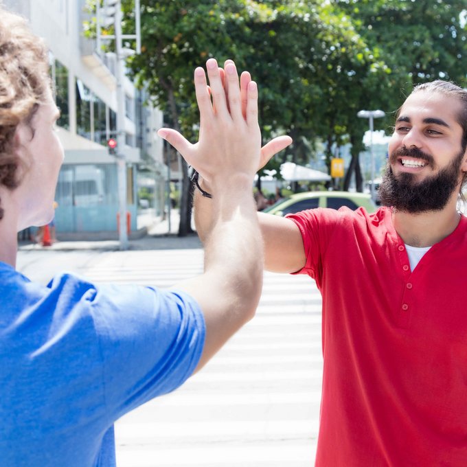Mann mit Bart klatscht Freund in blauem T-Shirt ab