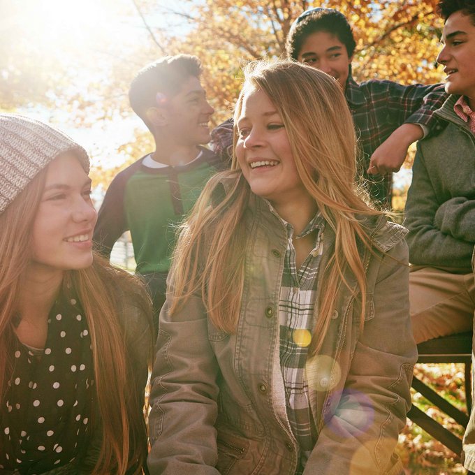 Gruppe junger Menschen sitzen in Herbstsonne im Park