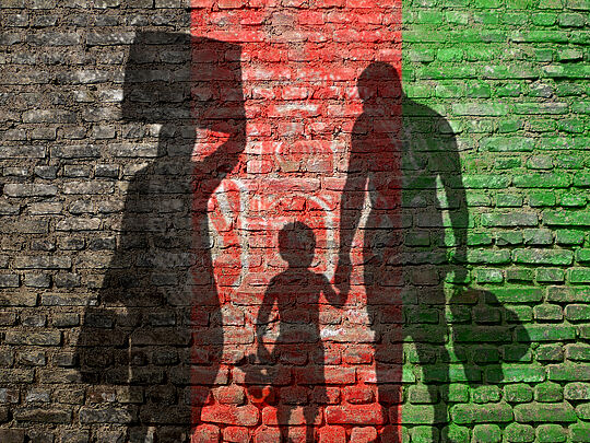 Afghanische Flagge schimmernd auf Hauswand mit Schatten einer Familie