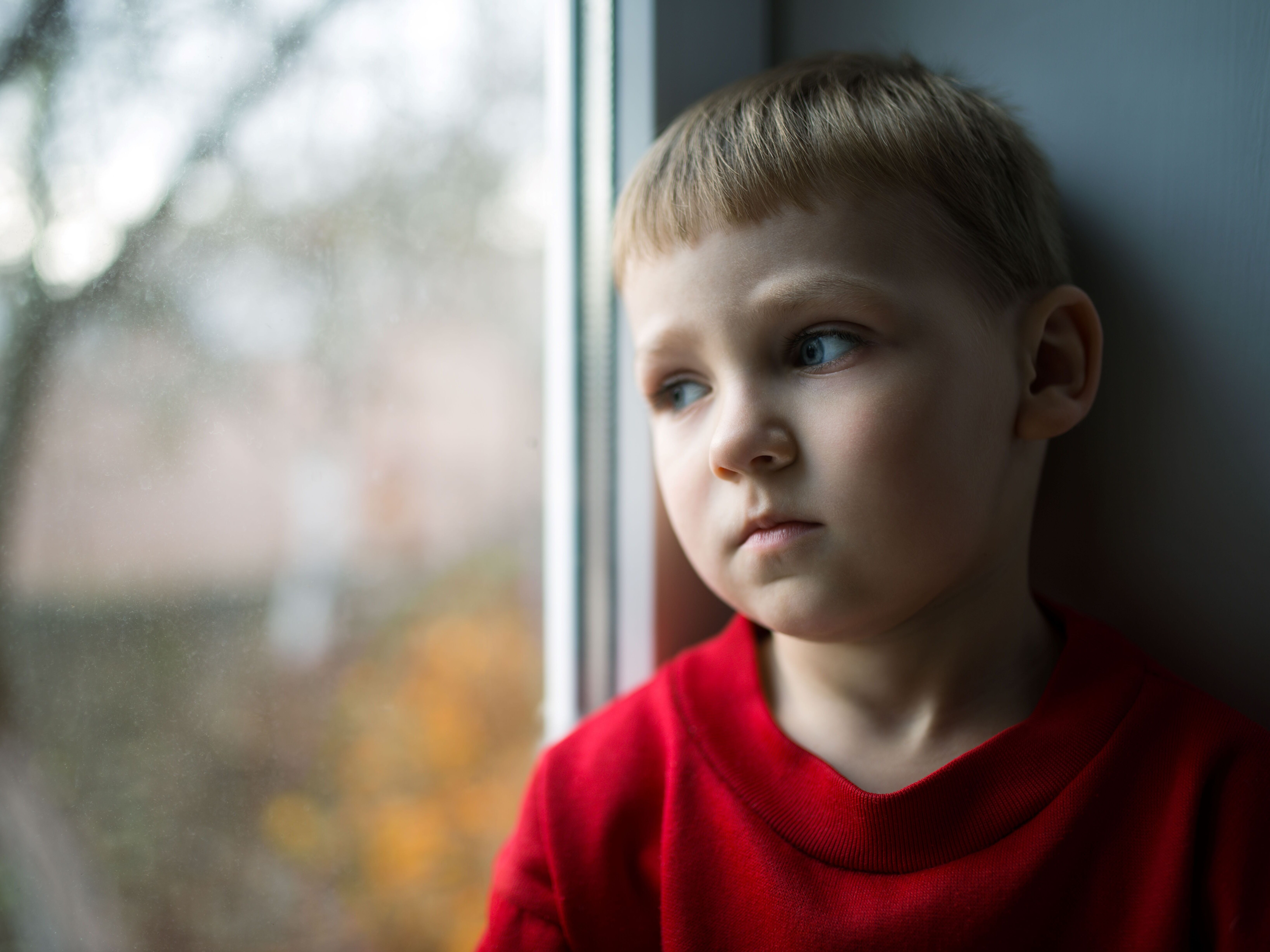 Kleiner Junge schaut traurig aus Fenster