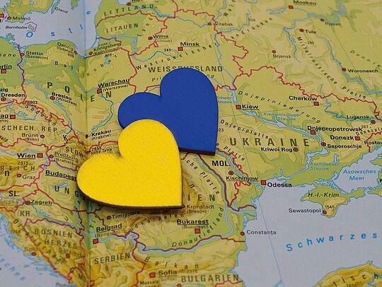 Auf Landkarte mit Umrissen der Ukraine liegen zwei Herzen in den Nationalfarben gelb und blau